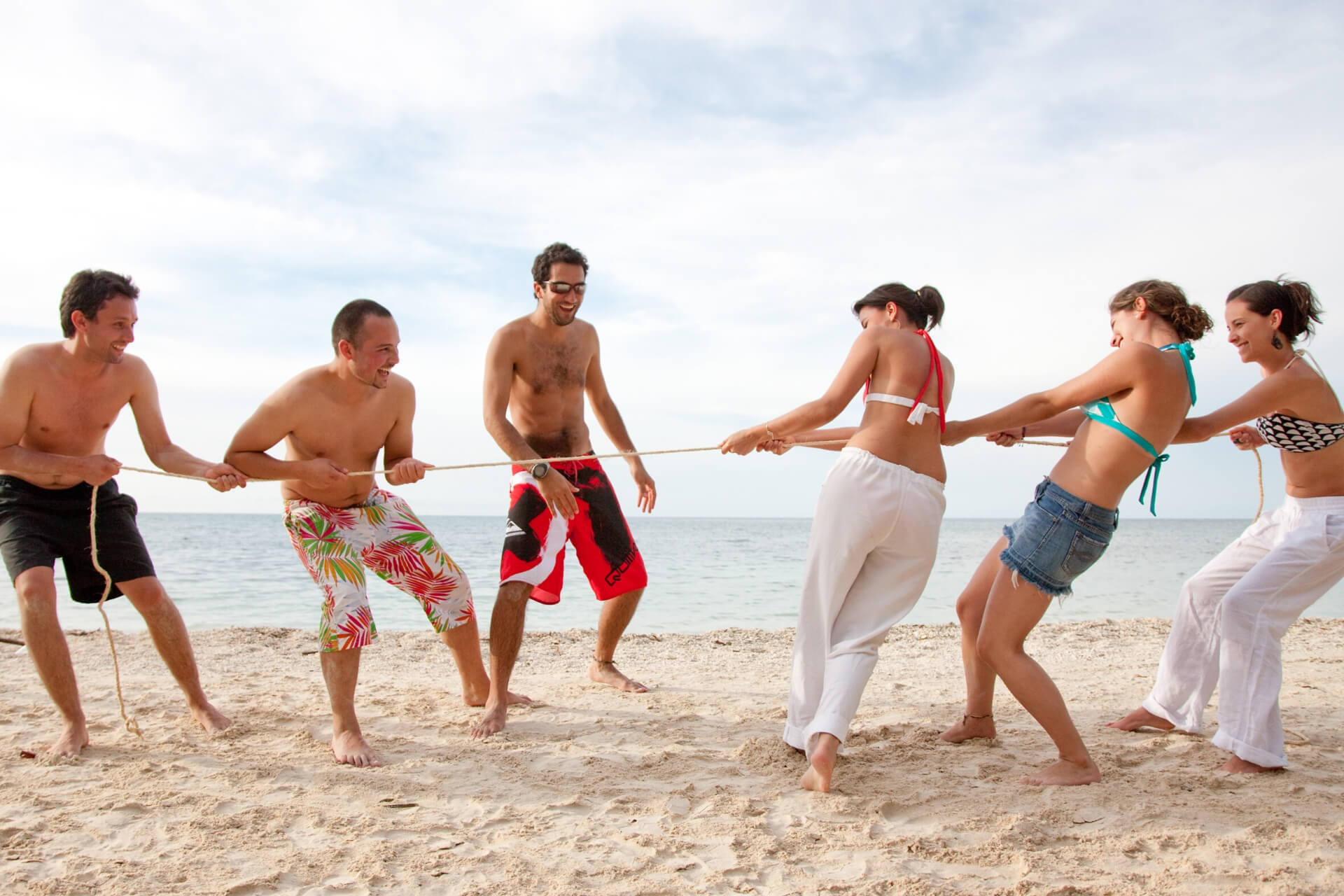 Конкурс мужчины против женщин. Перетягивание каната на пляже. Игры на пляже. Летние игры на пляже. Друзья на пляже.